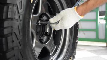 Human hand wearing white gloves tighten the wheel nuts with a wrench. video