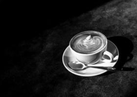 Taza de arte latte caliente en la luz de la tarde en la mesa de madera foto