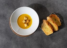 sopa de calabaza con crutones de pan en un plato de pan de ajo foto