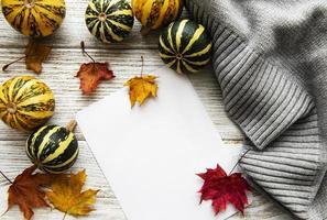 Autumn maple leaves, pumpkins and woolen scarf on a wooden background. photo