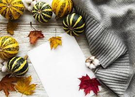 Autumn maple leaves, pumpkins and woolen scarf on a wooden background. photo