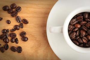 A cup with coffee and coffee beans on wood background photo