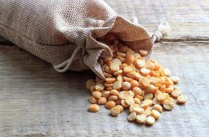 Dried peas in a sack lie on a wooden background photo