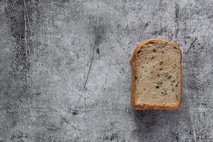 Sliced grain  whole wheat bread on dark rustic wooden background photo