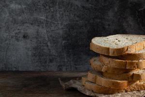 Sliced grain  whole wheat bread on dark rustic wooden background photo