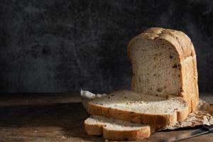 Sliced grain  whole wheat bread on dark rustic wooden background photo