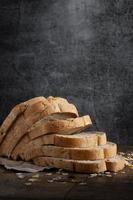 Sliced grain  whole wheat bread on dark rustic wooden background photo