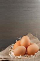 Fresh Organic eggs in burlap with dry grass on wood table. photo