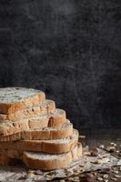 Primer plano de pan de trigo integral de grano en rodajas sobre fondo oscuro foto