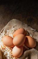 Fresh Organic eggs in burlap with dry grass on wood table. photo