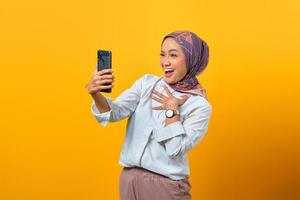 Emocionada mujer asiática mirando smartphone recibiendo buenas noticias foto