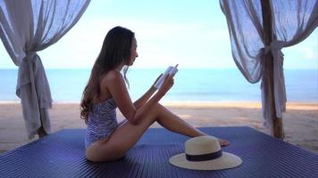 joven, mujer asiática, leer un libro, en la playa video