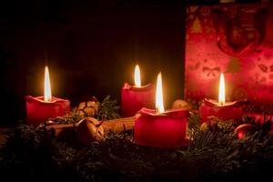 Decorated advent wreath made of fir branches with burning red candles photo