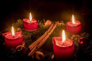 Decorated advent wreath made of fir branches with burning red candles photo