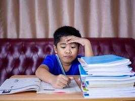 boy doing homework and reading on a wooden table. photo