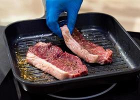 Beef steaks being prepared on grill , cooking meat steaks on kitchen photo