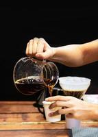 barista haciendo café, barista vertiendo café por goteo en un vaso foto