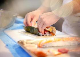 manos de chef preparando comida japonesa, chef haciendo sushi foto