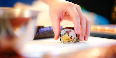 manos de chef preparando comida japonesa, chef haciendo sushi foto