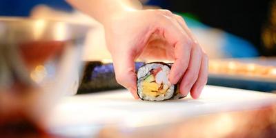 manos de chef preparando comida japonesa, chef haciendo sushi foto