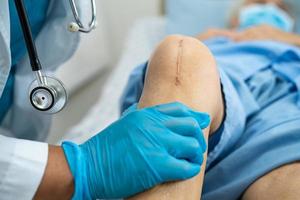 Paciente mayor asiático muestra sus cicatrices reemplazo quirúrgico de la articulación de la rodilla foto