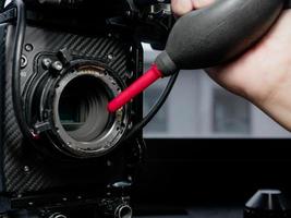 Using a rubber inflator to clean the sensor glass of the movie camera.
