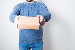 Anonymous young man with jeans delivering a cardboard box photo