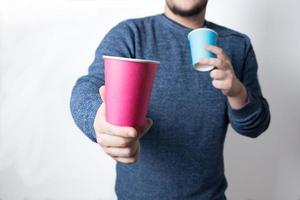 Young anonymous man offering a cardboard cup and holding another one photo