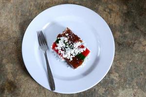 Layer cake and grated coconut on plate with cutlery, malay food photo