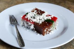 Layer cake and grated coconut on plate with cutlery, malay food photo