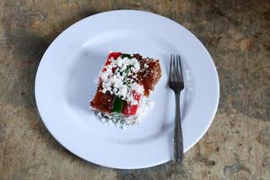 Layer cake and grated coconut on plate with cutlery, malay food photo