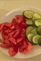 Fresh chopped tomatoes and cucumbers on a white plate photo