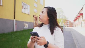 Asian woman walking and getting lost and trying to search on maps video