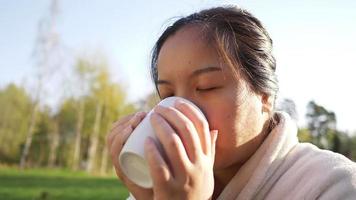 asiatische Frau, die am Morgen heißen Kaffee hält und trinkt video
