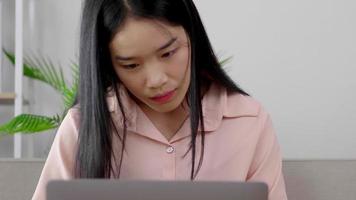 Vista frontal de la mujer asiática que trabaja en la computadora portátil escribiendo