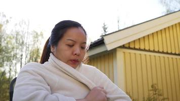 asiatisk kvinna som sitter på en stol utanför på morgonen video