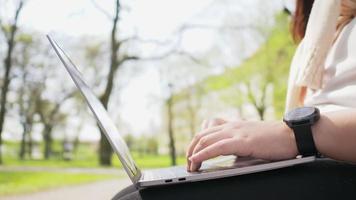 gros plan sur les mains d'une femme assise et travaillant sur un ordinateur portable au parc video