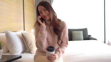 jonge aziatische vrouw die een smartphone in bed gebruikt video