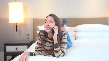 junge asiatische frau mit einem smartphone im bett video