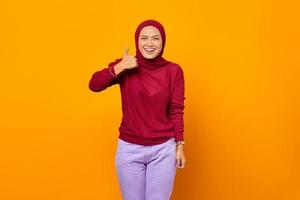 Happy Asian woman showing thumbs up and looking at camera photo