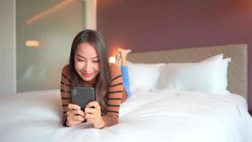 Young asian woman using a smartphone in bed video