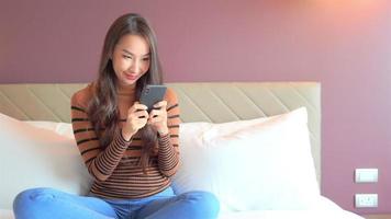 junge asiatische frau mit einem smartphone im bett video