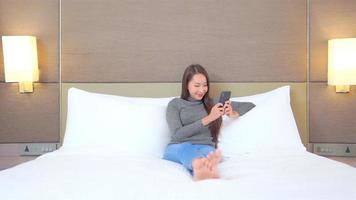 junge asiatische frau mit einem smartphone im bett video