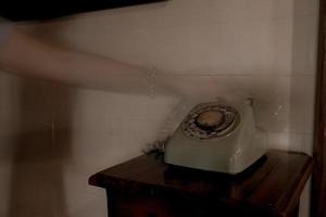 Mano de fantasma sosteniendo auriculares de teléfono retro en casa antigua foto