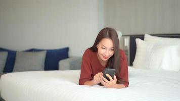 jovem mulher asiática usando um smartphone na cama video