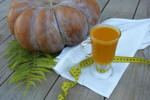 Pumpkin on a wooden background and a glass of pumpkin juice. photo