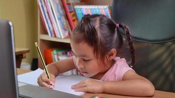 schattig klein schoolmeisje dat huiswerk wiskunde bestudeert tijdens haar online. video