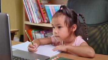 Cute little schoolgirl studying homework math during her online. video