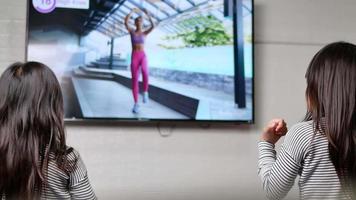 Little cute girls practicing yoga pose on a mat indoors. video