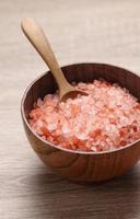 Himalayan pink salt in wooden cup on wooden table photo